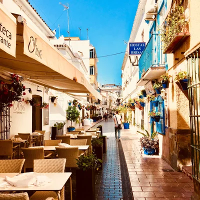 Terraza de un restaurante entre macetas y buganvillas en una calle blanca