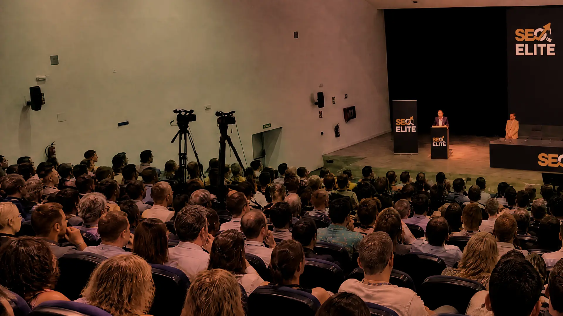 Charla de SEO Elite ante un auditorio lleno, con una gráfica de crecimiento proyectada en la pantalla